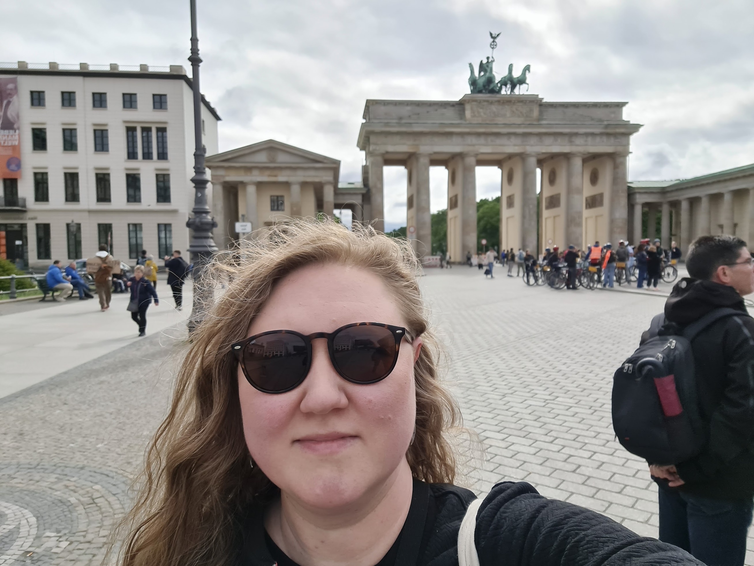 Selfie, jonka taustalla Berliinin Brandenburgin portti ja pilvinen taivas