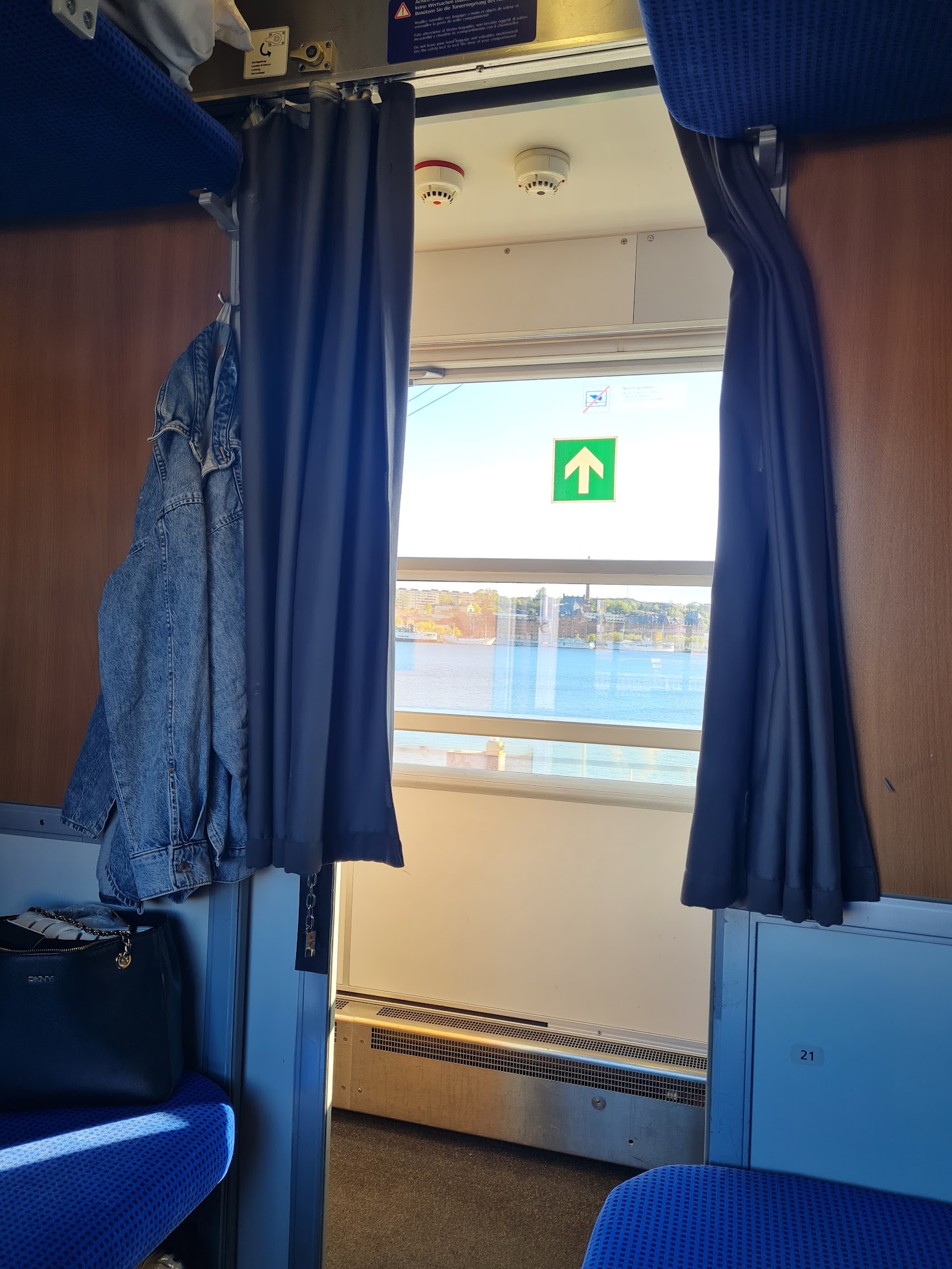 Junan hytistä näkyy käytävälle ja sen läpi ulos. Taustalla ulkona näkyy vettä ja sininen taivas