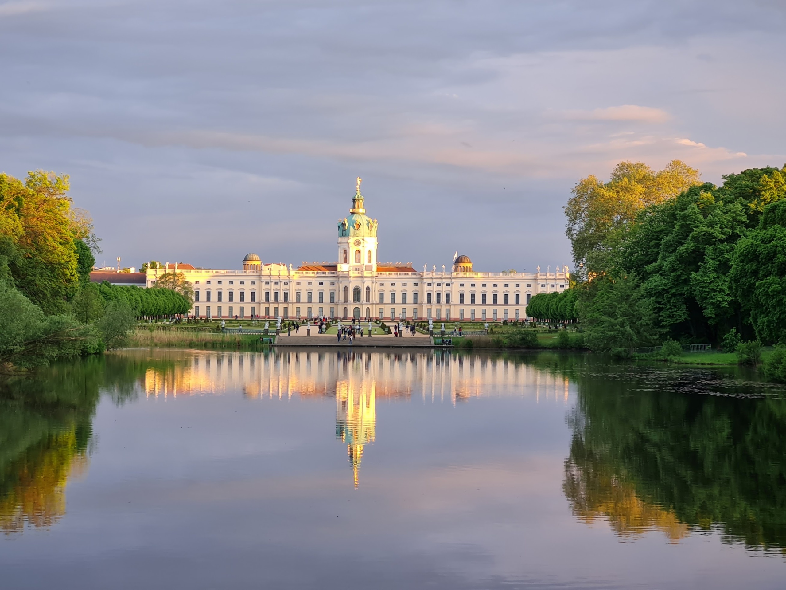 Palatsi, joka heijastuu lammen pintaan ja taivasta värjää iltarusko.