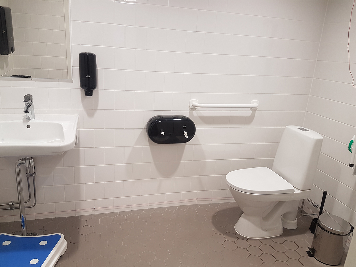 Esteettömän ja tilavan  WC:n sisustus, korokejakkara ja tavanomainen wc:n kalustus.
